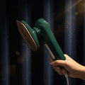 Green handheld shower head held by a hand with a white background